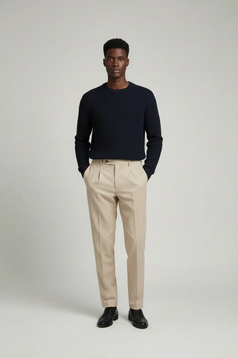 Modello con maglione blu scuro e pantaloni beige eleganti, moda uomo elegante.