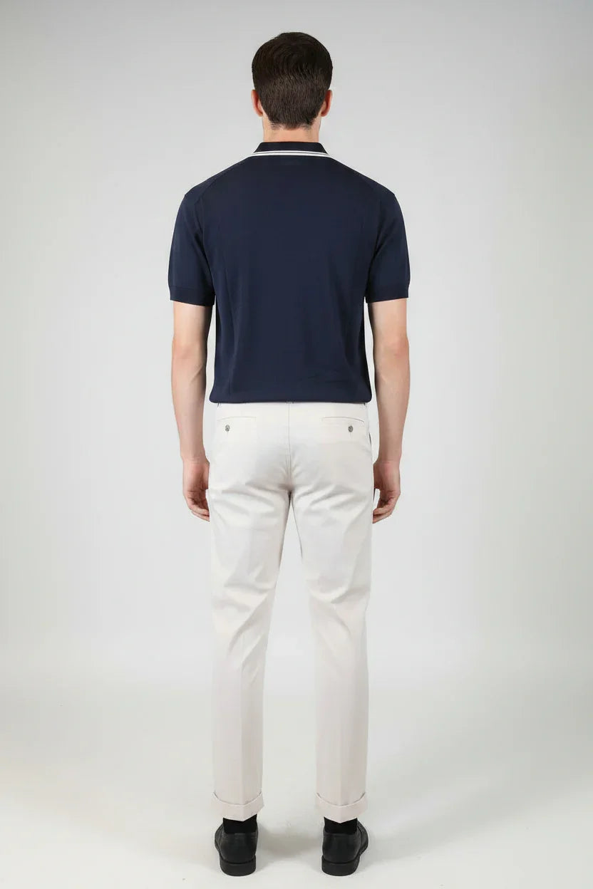 Uomo di spalle con polo blu navy e pantaloni eleganti bianchi, moda uomo elegante